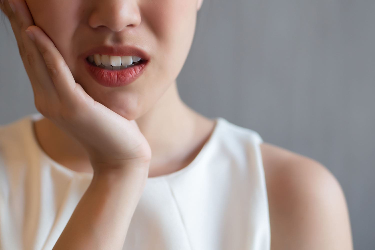 親知らずの痛みで頬を押さえる女性